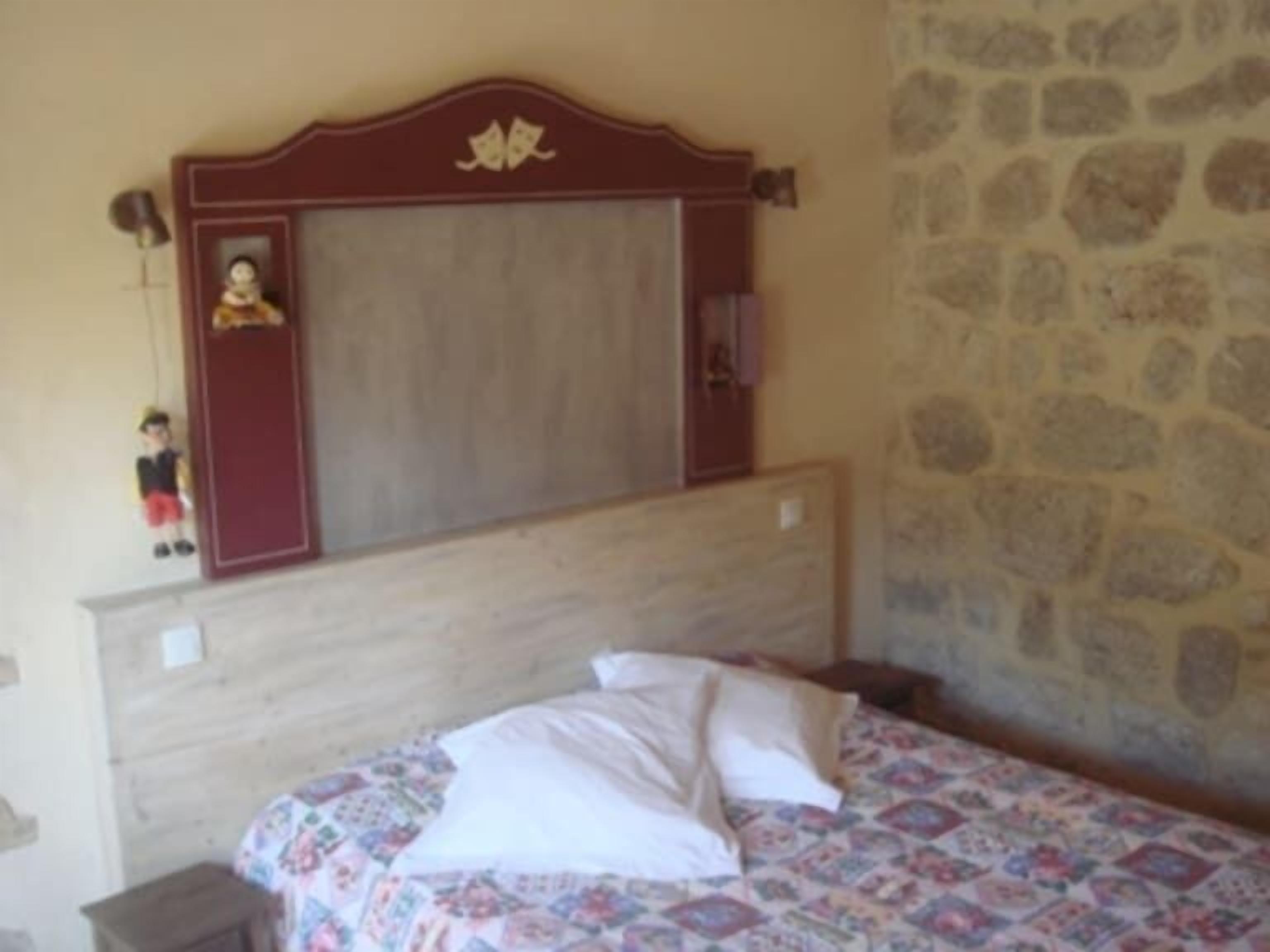 Un dormitorio con cabecera de madera, cama con colcha estampada floral y pared de piedra.
