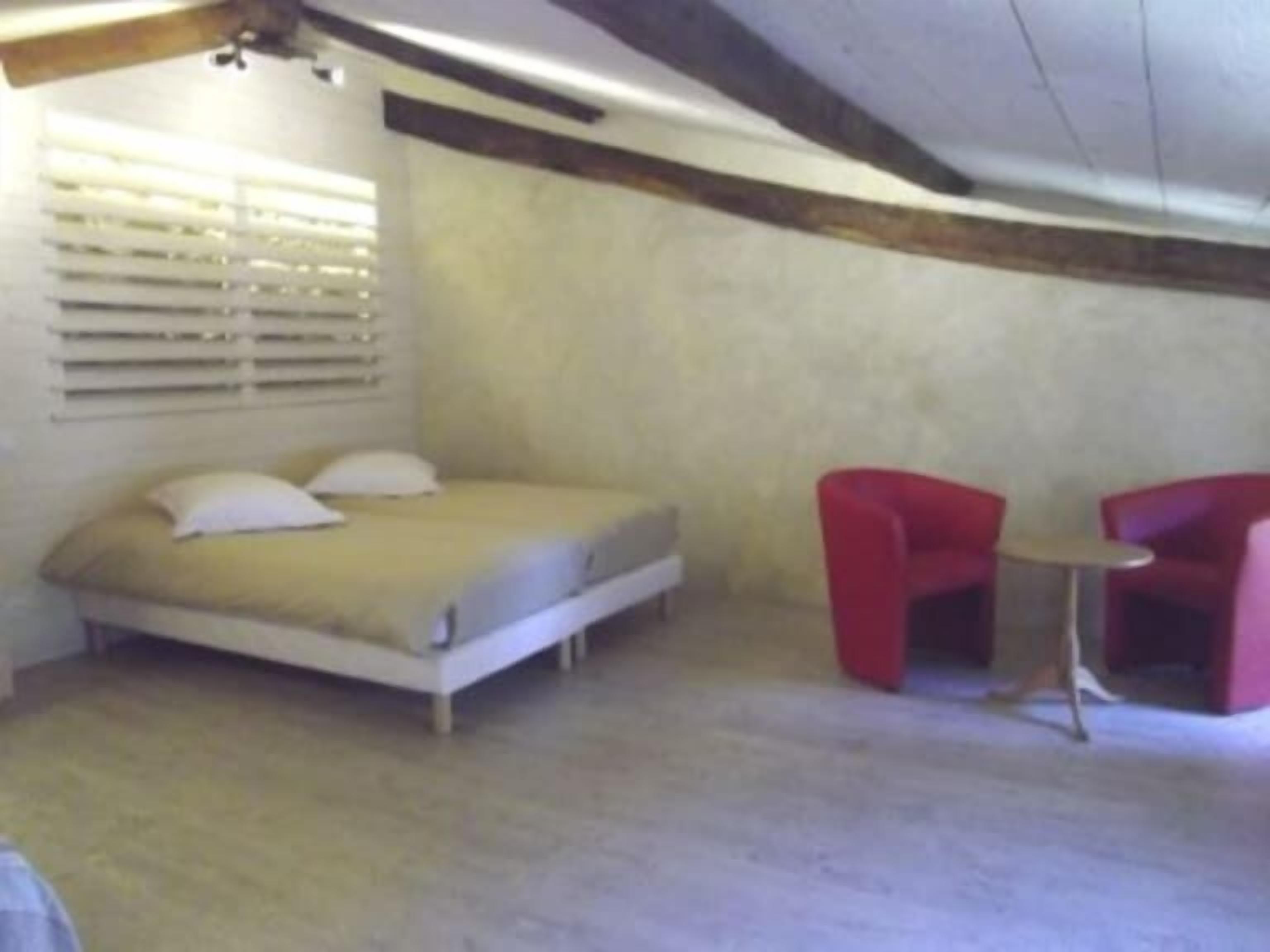 Une chambre à coucher avec un lit, une petite table et deux chaises rouges.