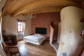 Cozy retreat with a loft-style design, featuring a large bed and a wooden desk near a window.