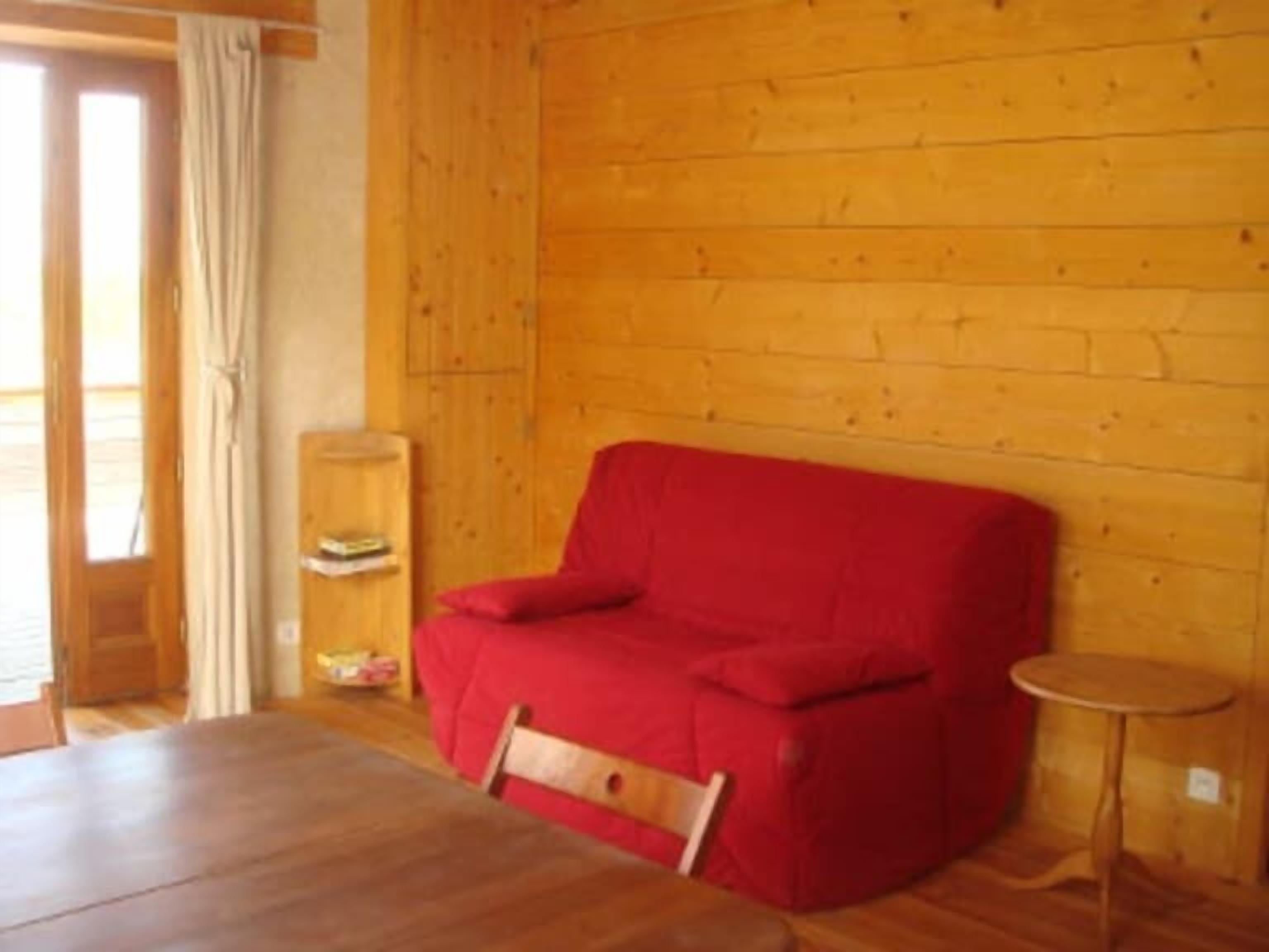 A cozy room with a wooden floor, a red sofa, a small wooden table, and a wooden cabinet.