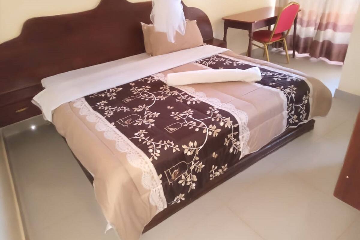 A neatly made bed with a floral-patterned bedspread and a white pillow.