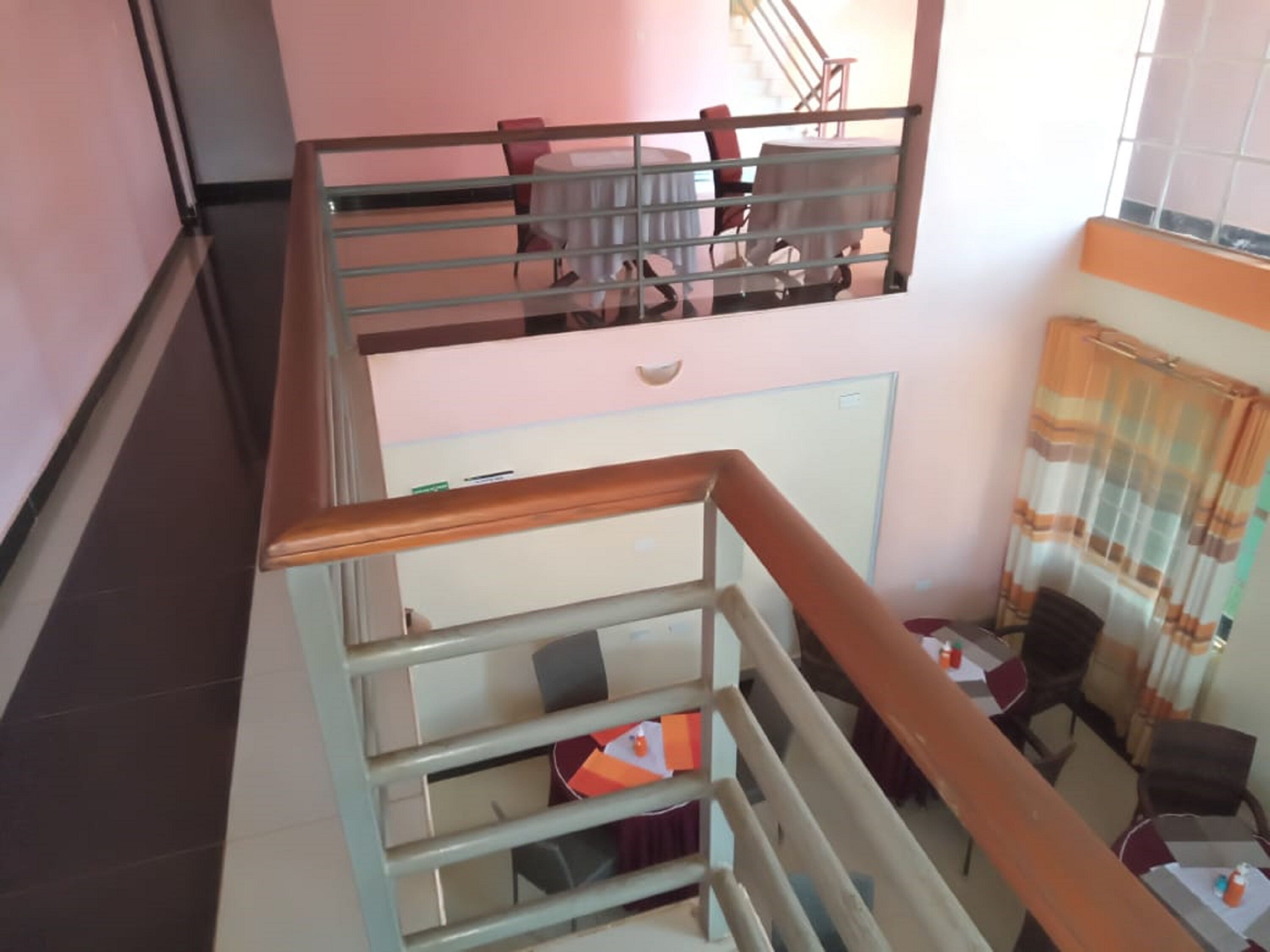 Ein mehrgeschossiges Interieur mit einer Treppe, einem Essbereich und Blick auf eine weitere Treppe, die zu einer anderen Ebene führt.