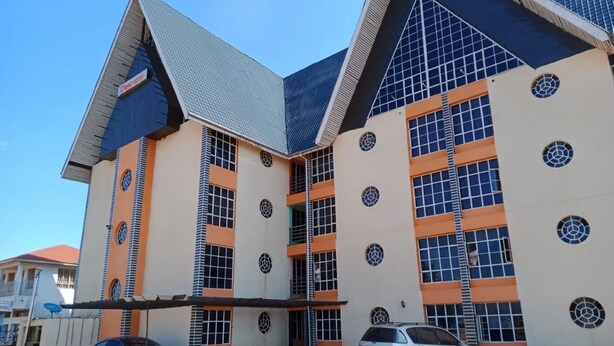 A multi-story building with a modern architectural design, featuring large windows and a distinctive geometric pattern on the facade. - Drimz Hotel Busia (Busia)