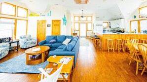 Ein geräumiges Wohnzimmer mit einem blauen Sofa, einem Holztisch und einem Essbereich mit Holzkästen.