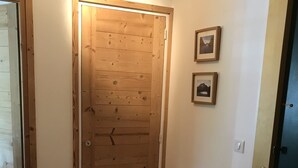 A wooden door with a light fixture above it, a small bench with a bag and shoes, and two framed pictures on the wall. - Spacious 2-bed apartment in Morzine on ski bus route (Morzine)