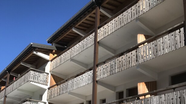 A multi-story building with balconies, a sign indicating a property for sale, and snow on the ground. - Spacious 2-bed apartment in Morzine on ski bus route (Morzine)