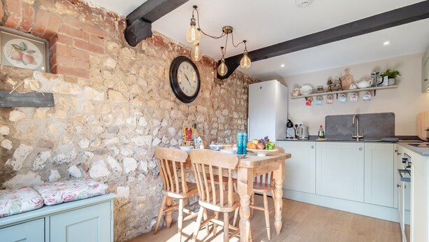 Une cuisine rustique avec des murs en pierre, des meubles en bois et une horloge.