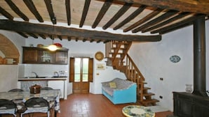 Un ambiente rustico con zona pranzo, cucina e una scala che conduce a un piano superiore.