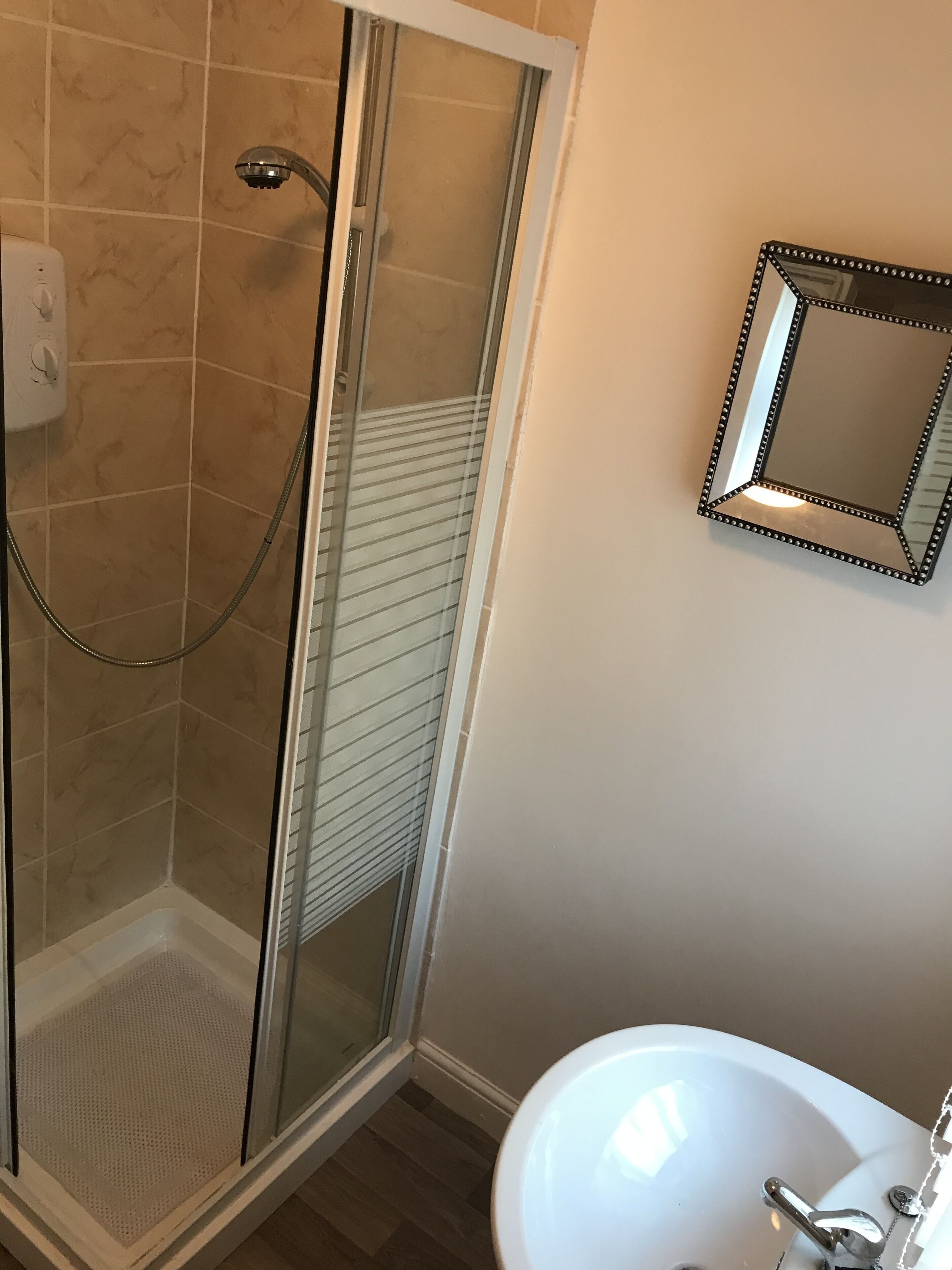A bathroom with a shower, a sink, and a mirror.
