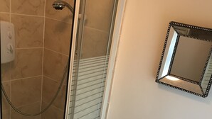 Ein Badezimmer mit Dusche, Waschbecken und Spiegel.