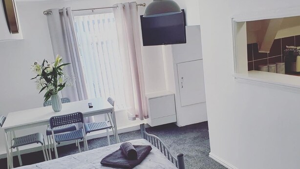 Ein Hotelzimmer mit Bett, Schreibtisch, Stuhl, Fernseher und Fenster.