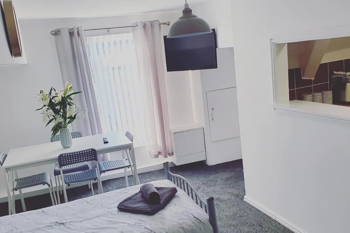 A hotel room with a bed, a desk, a chair, a TV, and a window.