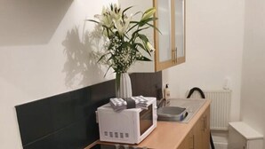 Eine moderne Küche mit einem schwarzen Induktionskochfeld, weißen Geräten und Holzschränken.
