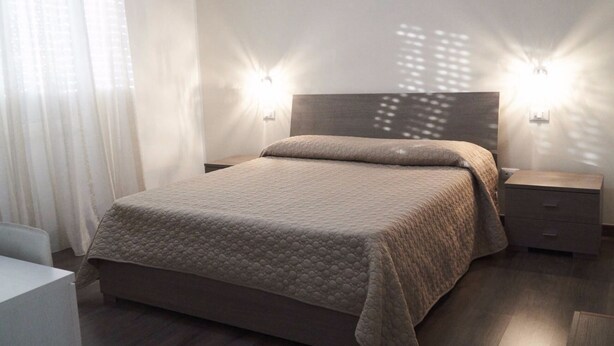 A modern bedroom with a large bed, two bedside tables, and a headboard. - La Perla Del Sole (Corigliano-Rossano)