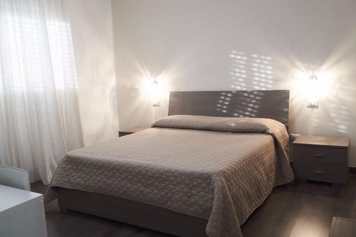 A modern bedroom with a large bed, two bedside tables, and a headboard.