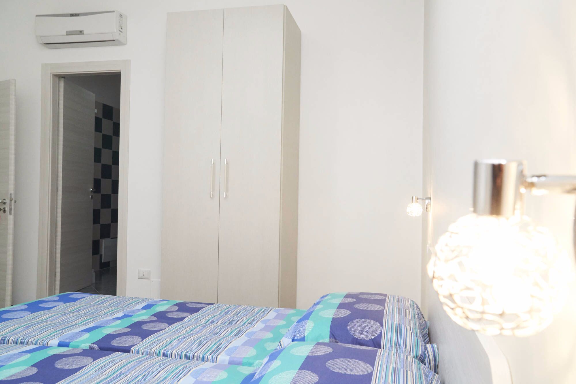 Un dormitorio con cama, armario y aire acondicionado instalado en la pared.