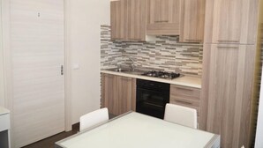 A compact kitchen with wooden cabinets, a tiled backsplash, and a gas stove. - La Perla Del Sole (Corigliano-Rossano)