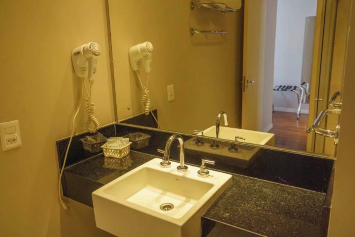 Baño con lavamanos, espejo, secador de pelo y toallero.