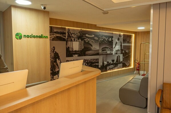 A reception area with a wooden desk, a large wall displaying historical photos, and a fire extinguisher. - Hotel Nacional Inn Porto Alegre (Porto Alegre)