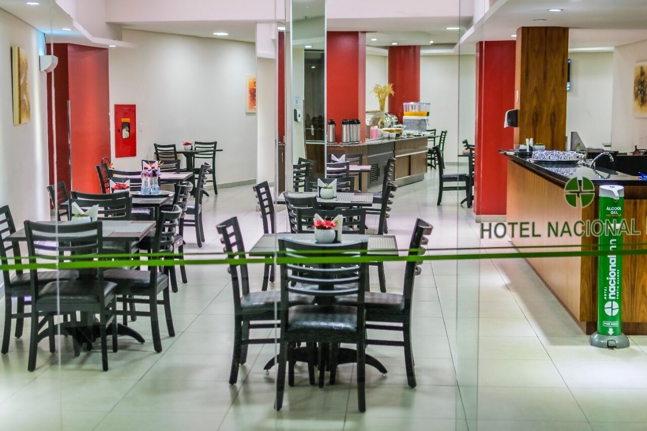 En hotellrestaurang med flera bord och stolar, en receptionsdisk och en bardisk med en skylt som visar texten ”HOTEL NACIONAL”.