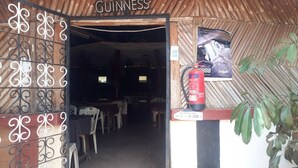 A doorway with a sign reading "GUINNESS" above it, leading into a dimly lit interior. A fire extinguisher is mounted on the wall to the right.