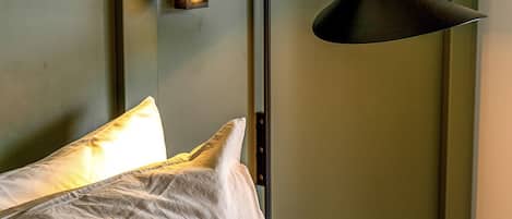 A bed with pillows and a nightstand with a lamp.