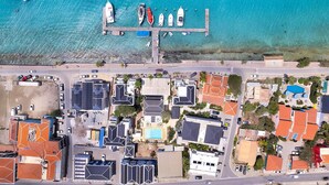 An aerial view of a coastal area with a marina, buildings, and a road.