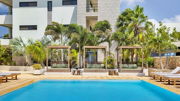A swimming pool with lounge chairs and a covered seating area.
