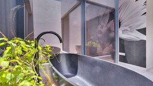 A modern kitchen with a large window, a black sink, and a potted plant.