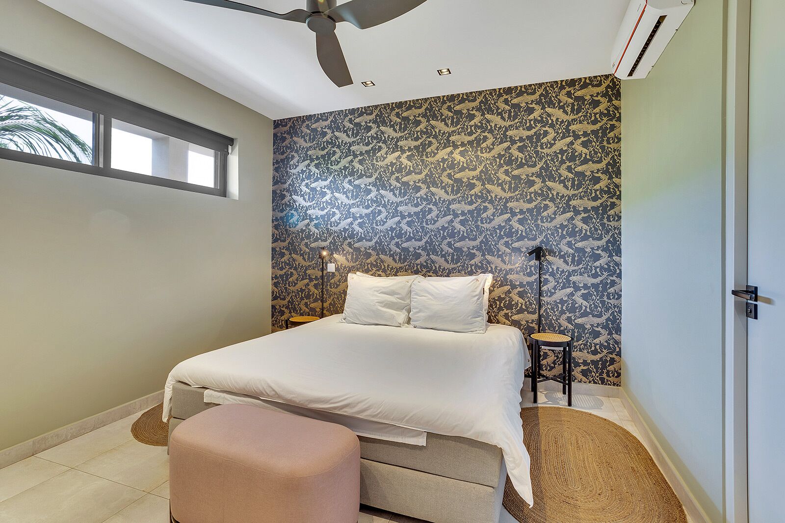 Une chambre à coucher avec un lit, une table de chevet, une lampe sur pied et une fenêtre.