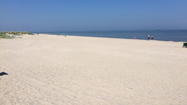 A wide sandy beach with a clear blue sky.