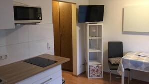 A compact kitchenette with a microwave, a small cabinet, and a wooden door.