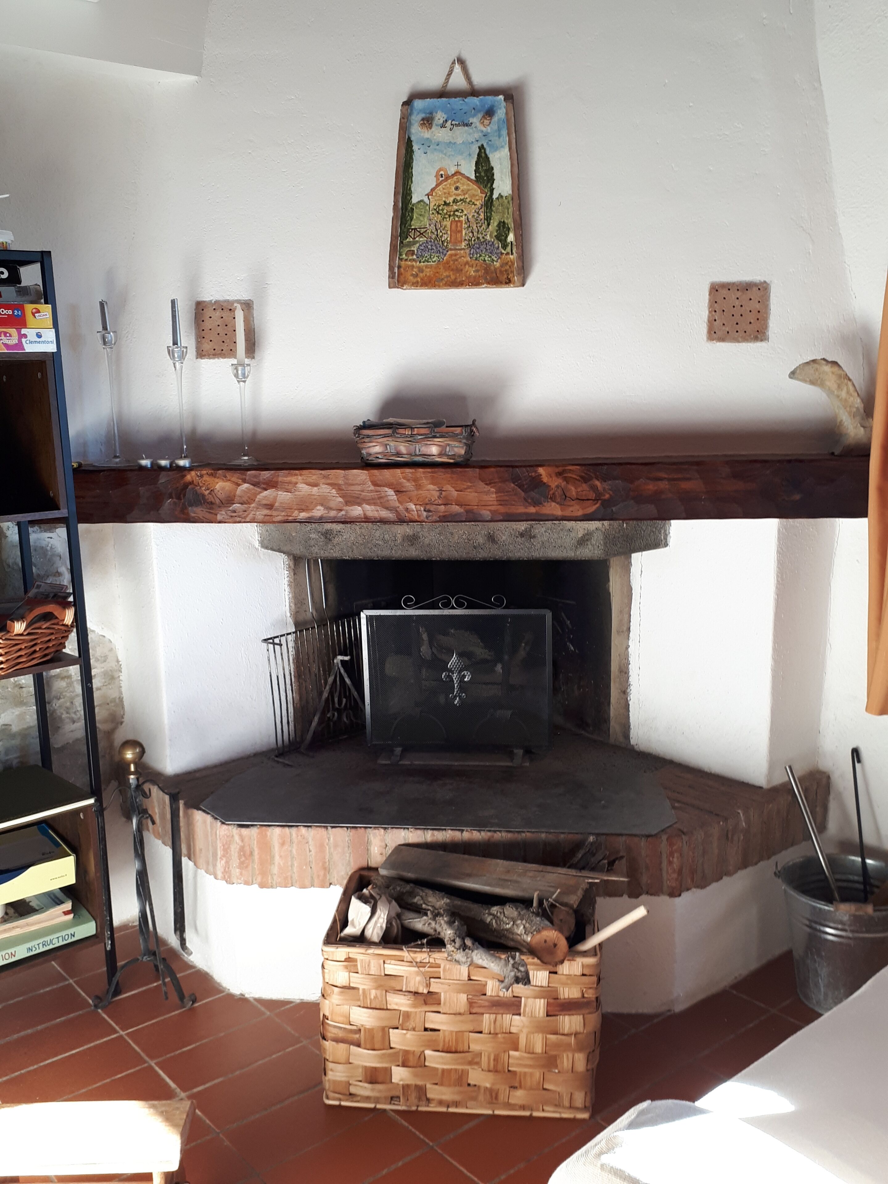 Ein rustikaler Innenraum mit Kamin, einem gewebten Holzkorb und einem Wandbild.
