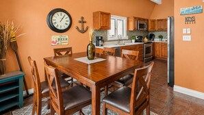 A kitchen with wooden cabinets, a stainless steel refrigerator, and a clock on the wall.