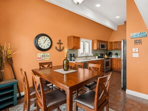 A kitchen with wooden cabinets, a stainless steel refrigerator, and a clock on the wall.