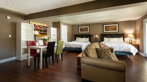 A hotel room with two beds, a dining area with a table and chairs, and a sofa.