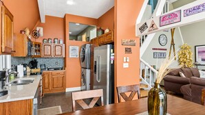 A modern kitchen with wooden cabinets, stainless steel appliances, and a dining area with a wooden table and chairs.
