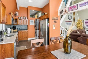A modern kitchen with wooden cabinets, stainless steel appliances, and a dining area with a wooden table and chairs.