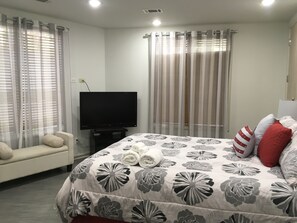 Een hotelkamer met een bed, een televisie, een bank en gordijnen.
