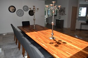 Een eetruimte met een lange houten tafel, meerdere stoelen en twee kandelaars.