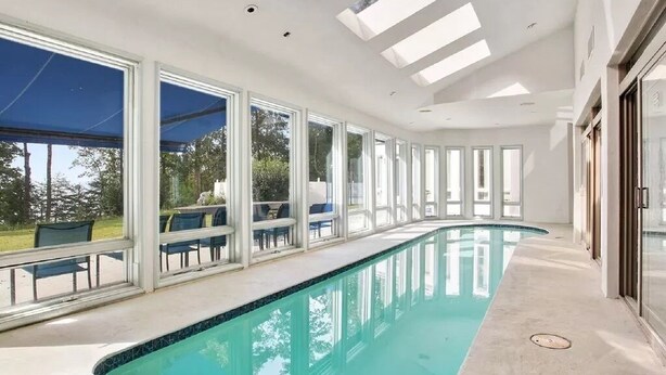 Una piscina interna moderna con ampie finestre e un lucernario.