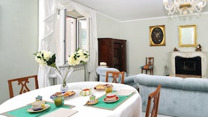 Un coin repas avec une table ronde dressée pour le petit-déjeuner, un canapé et une cheminée.