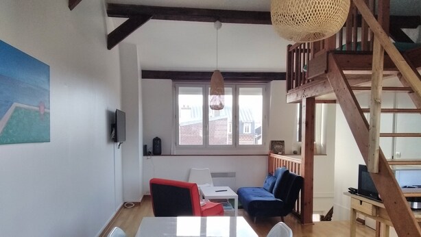 Una sala de estar moderna con una mesa blanca, sillas, un sofá y una escalera.