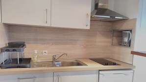 Una cocina moderna con un lavamanos de acero inoxidable, una cafetera y un escurreplatos.