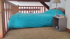Un dormitorio con cama, mesita de noche, lámpara y vistas al exterior.