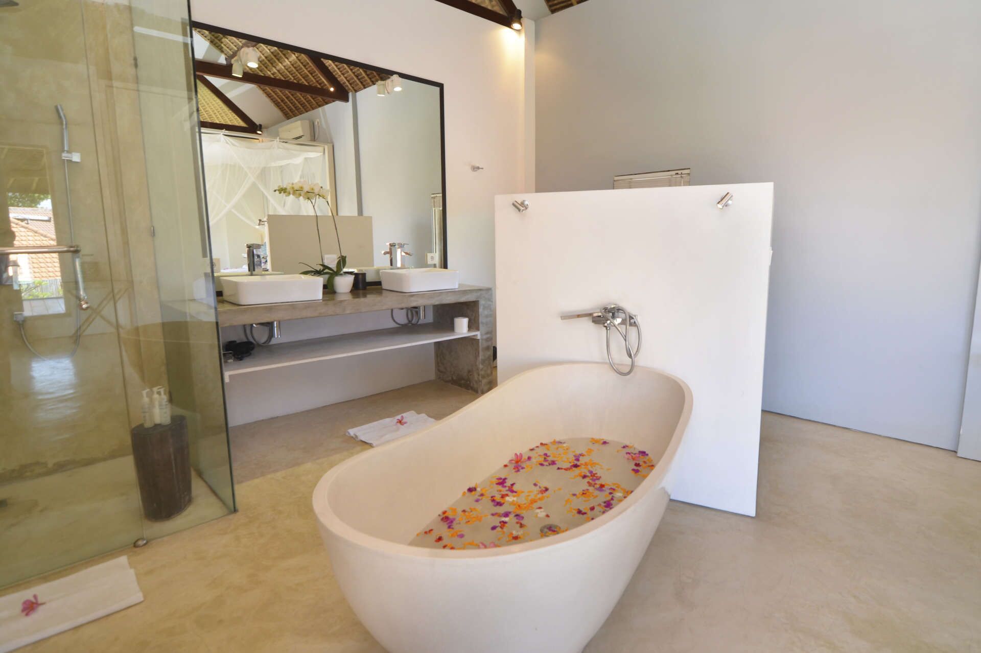 A modern bathroom with a freestanding bathtub, glass shower enclosure, and a large mirror.