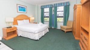 A hotel room with a bed, a chair, a wardrobe, a nightstand, a lamp, and a painting on the wall. - 651 Studio Apartment Hollywood Beach (Hollywood)