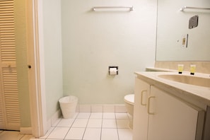A bathroom with a toilet, sink, and trash can.