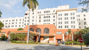 Un hôtel arborant une enseigne bien visible indiquant « Hollywood Beach Resort », caractérisé par un style architectural moderne avec un toit plat et de nombreuses fenêtres.