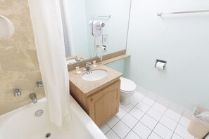 Ein Badezimmer mit Badewanne, Waschbecken, Toilette und einem an der Wand befestigten Föhn.